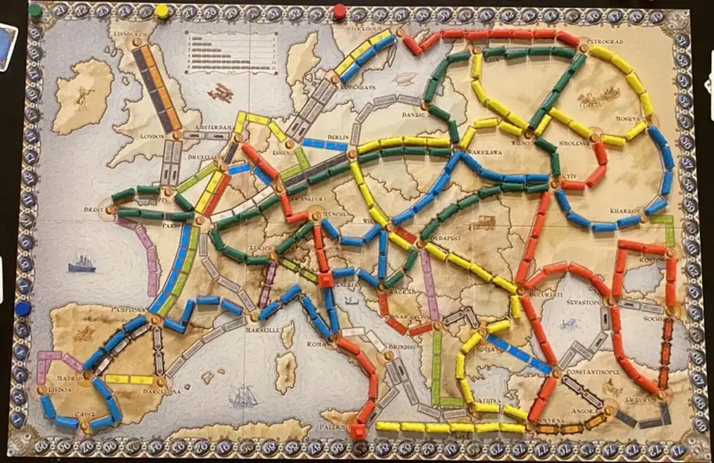 Een kleurrijke bordspelkaart van Europa toont onderling verbonden routes met rode, blauwe, groene, gele en zwarte paden. Steden zijn met elkaar verbonden in een strategisch netwerk.