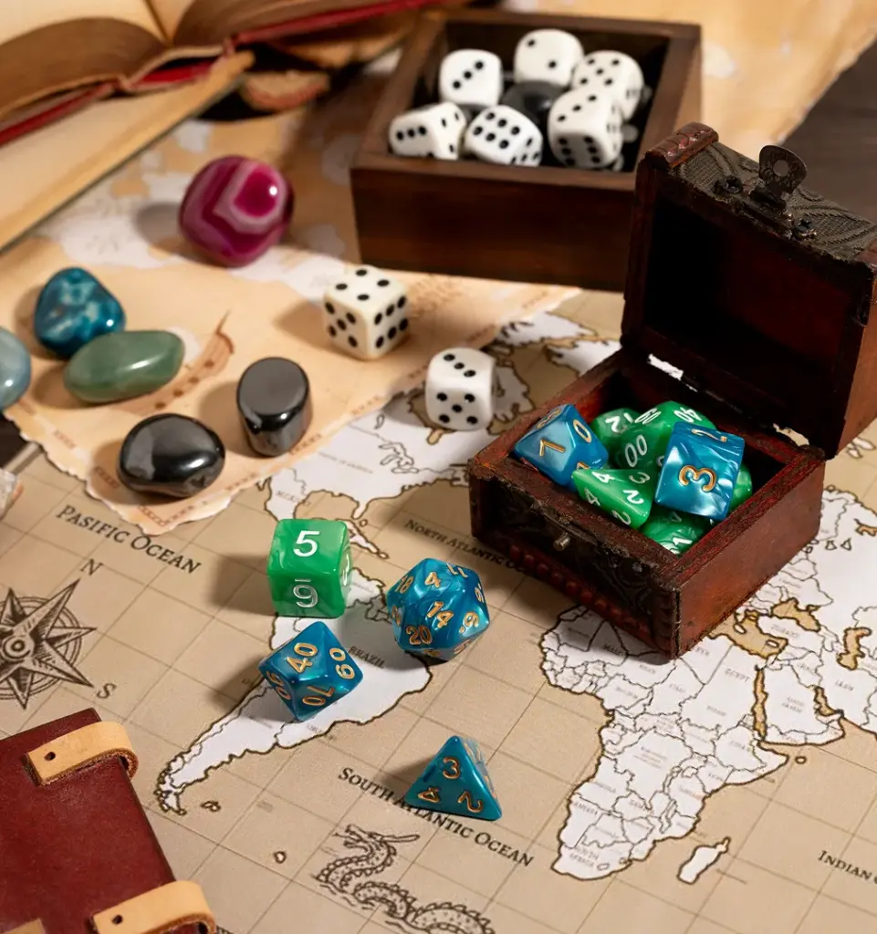 Een open boek, dobbelstenen, edelstenen en een schatkist met kleurrijke dobbelstenen liggen verspreid over een vintage wereldkaart, wat een avontuurlijke, speelse sfeer oproept.