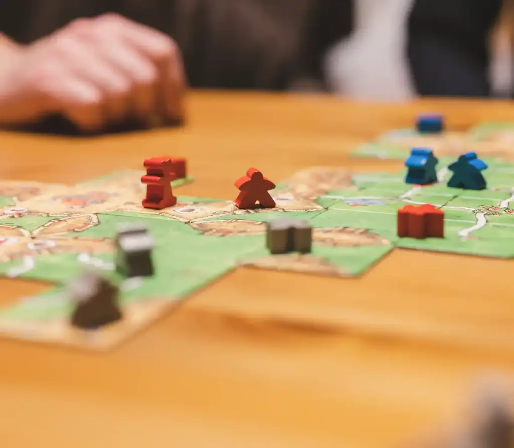 Een groep mensen verzamelde zich rond een tafel om een kleurrijk driehoekig puzzelspel te spelen, met drankjes in de buurt, wat teamwork en ontspannen plezier uitstraalde.